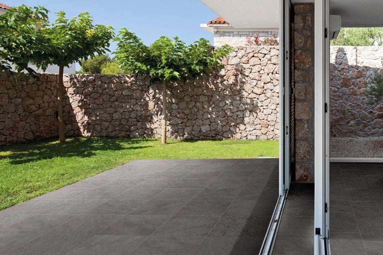 Terrasse avec mur en pierre, arbres et dalles de sol