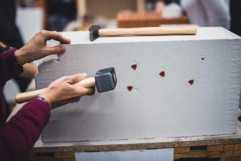 Un bloc de béton cellulaire est fixé à l'aide d'un marteau et d'une ancre.