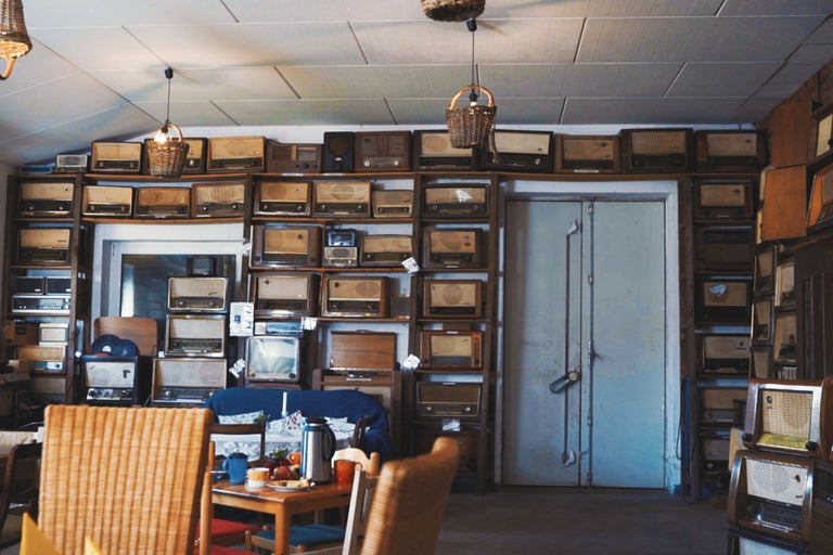 Intérieur avec des étagères remplies de vieilles radios, une table et des chaises