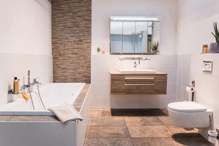 Salle de bains moderne avec baignoire, lavabo, armoire de toilette et toilettes pour une atmosphère lumineuse et conviviale