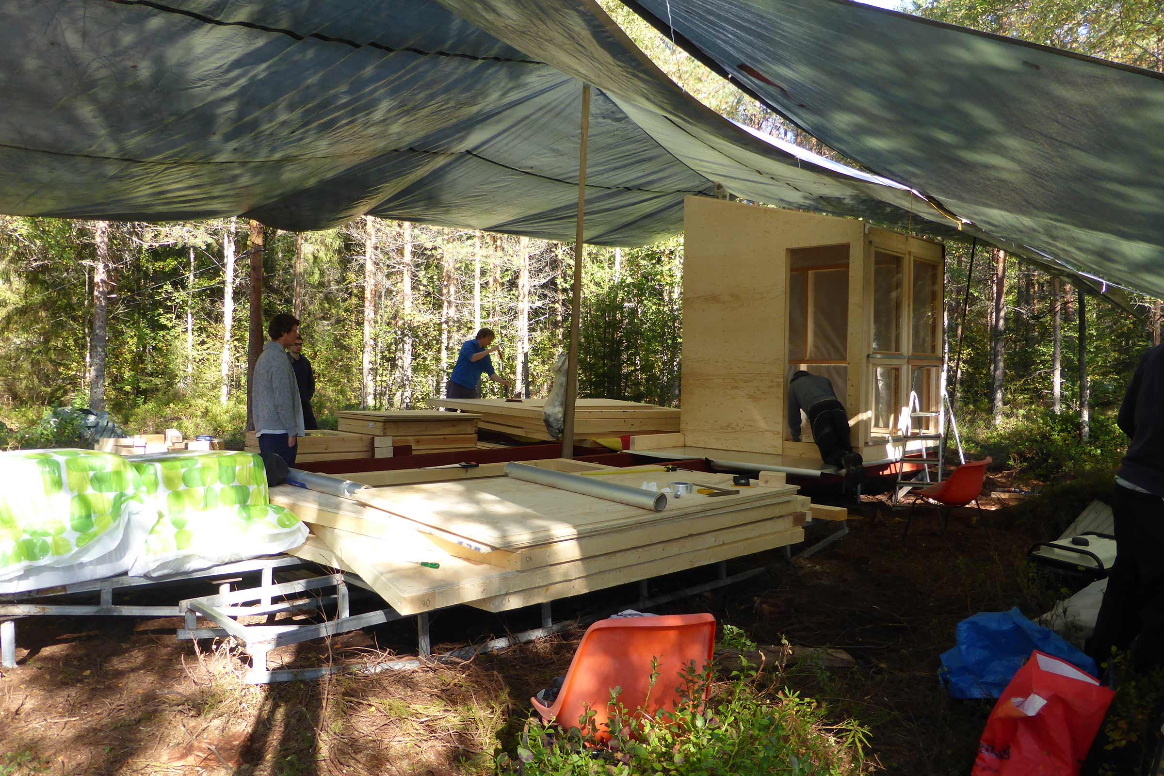 Construction d'une cabane en bois dans la forêt avec des panneaux de bois et des bâches