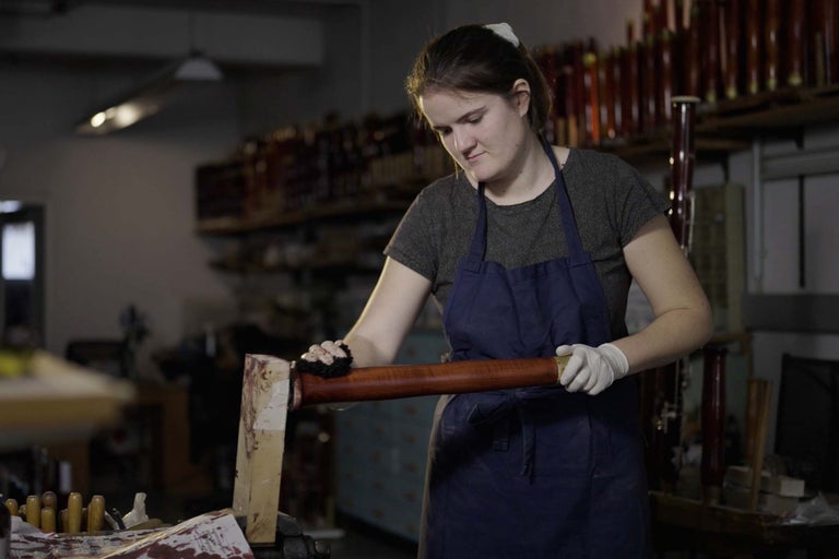 Femme travaillant une tige en bois dans un atelier