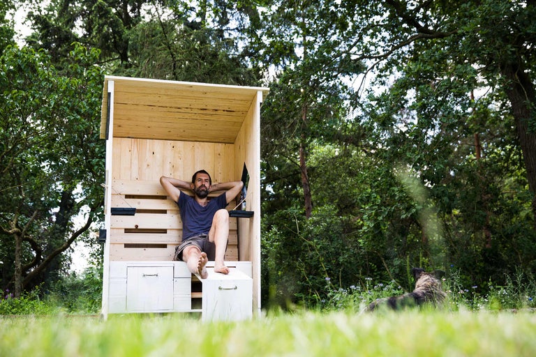 Homme se détend dans une cabane de plage en bois dans le jardin, à côté d'un chien