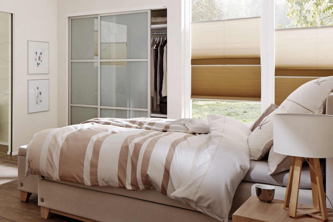 Schlafzimmer mit Doppelbett, Schiebetürenschrank und Plissee Rollos