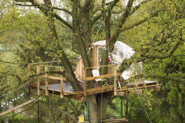 Baumhaus mit Holzterrasse und Hängebrücke im Garten