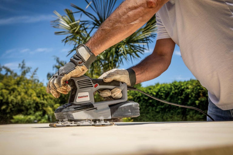 Une personne utilise une ponceuse vibrante Pattfield pour poncer une surface en bois.