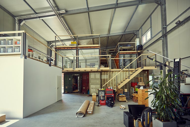Vue intérieure d'un hall d'usine spacieux avec des conteneurs, des escaliers et du matériel d'atelier