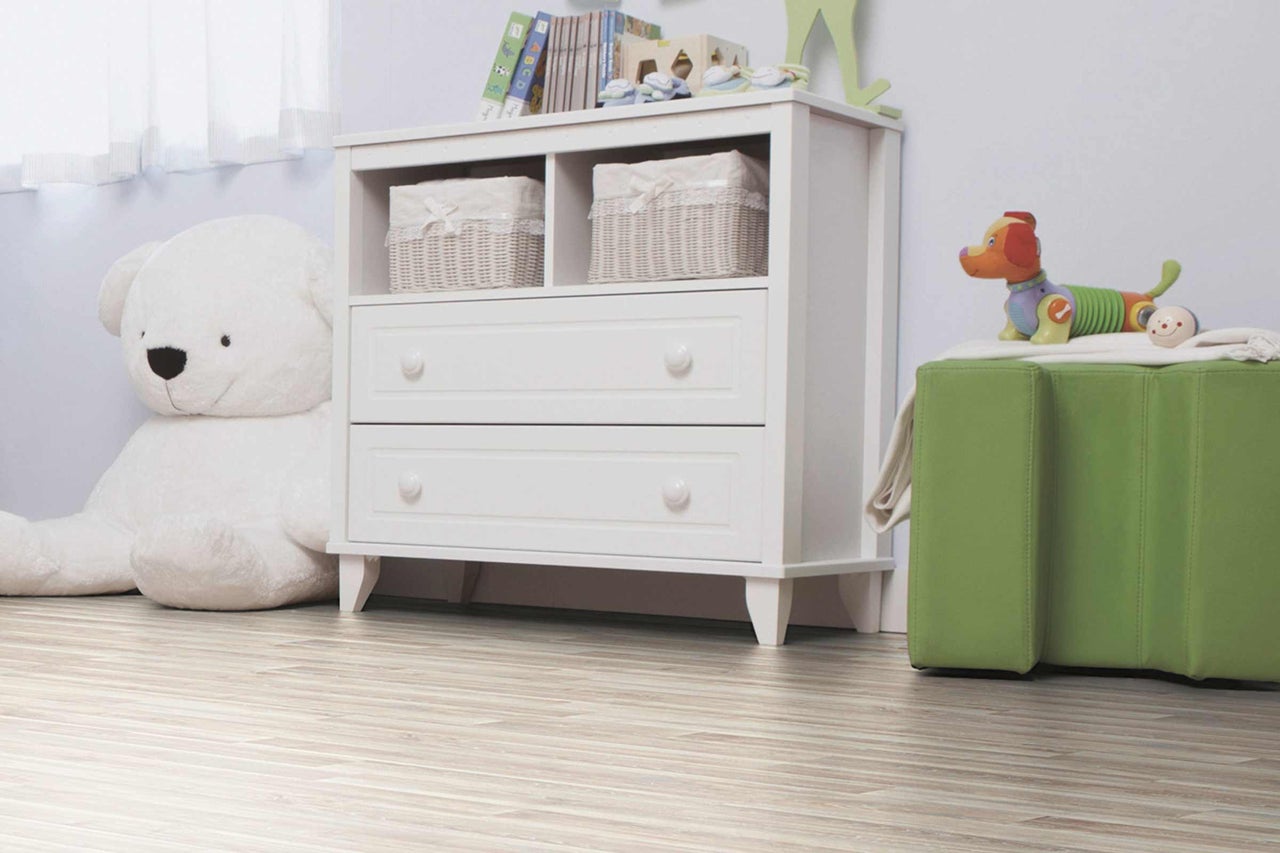 Chambre d'enfant avec commode blanche, jouets et plancher en bois