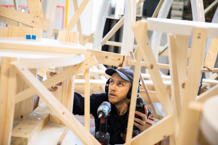 Un homme assemble une structure en bois avec une perceuse sans fil