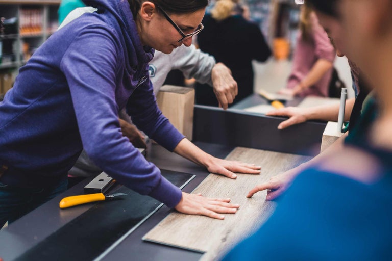 Des personnes posent du stratifié avec un cutter sur une surface plane.