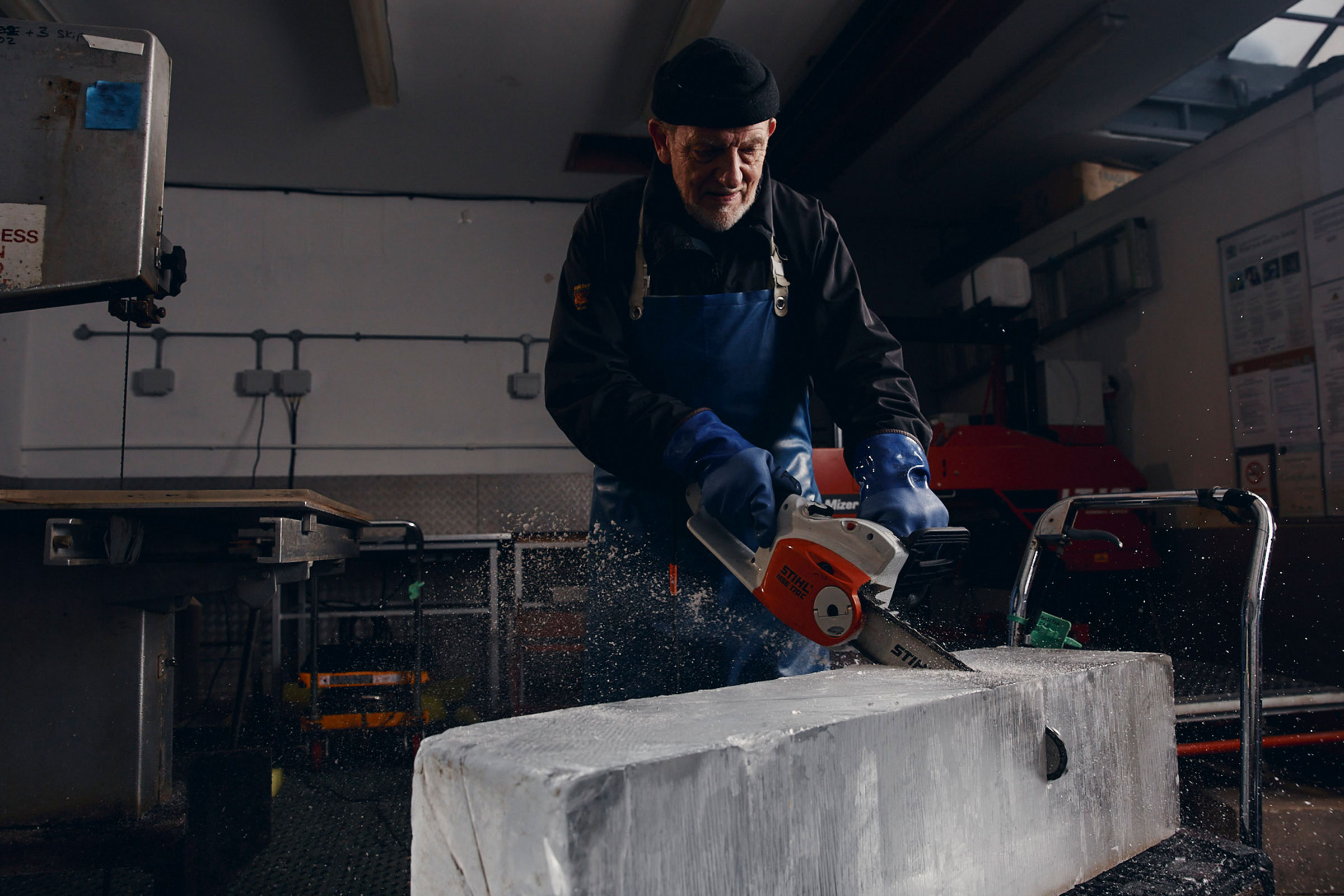 Mann sägt Eisblock mit einer Stihl Kettensäge