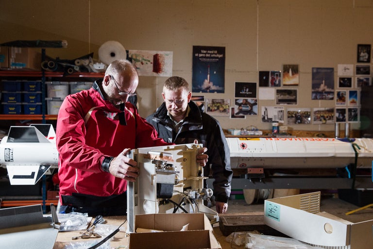 Deux personnes travaillent sur une fusée dans un atelier.