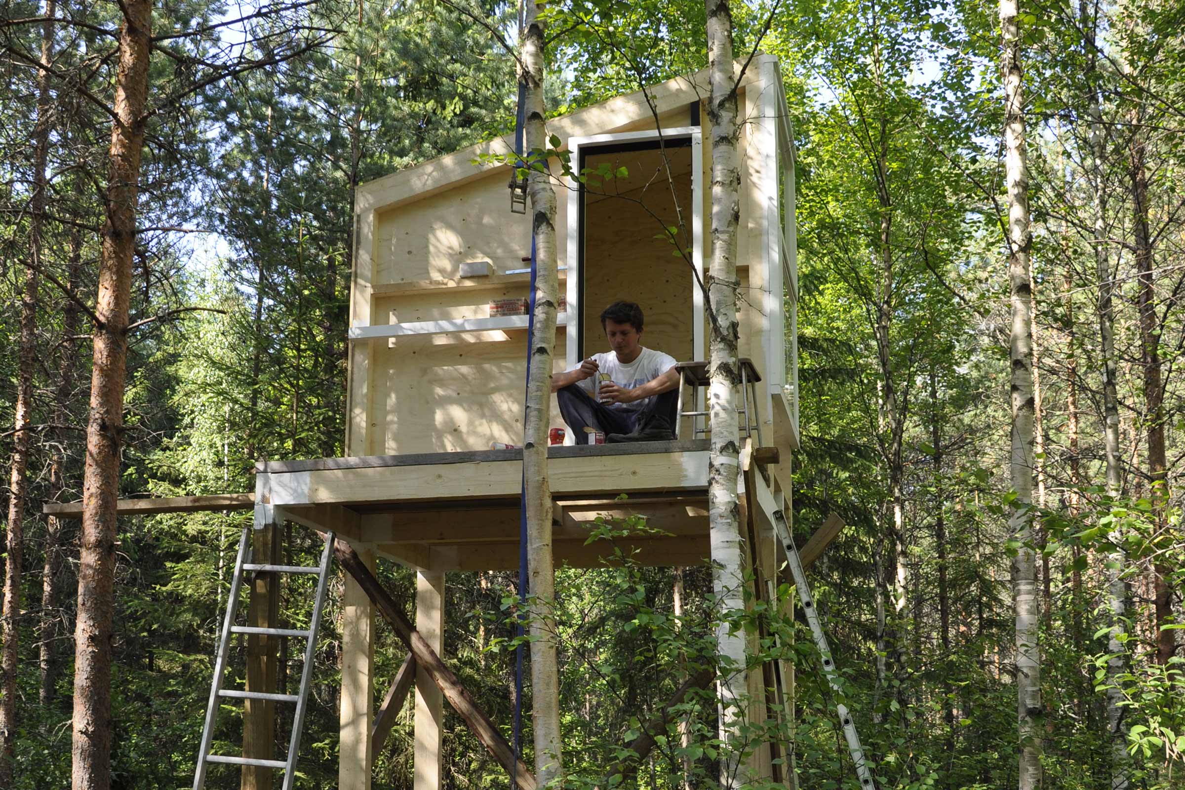 Cabane en bois avec échelle dans une forêt avec un homme