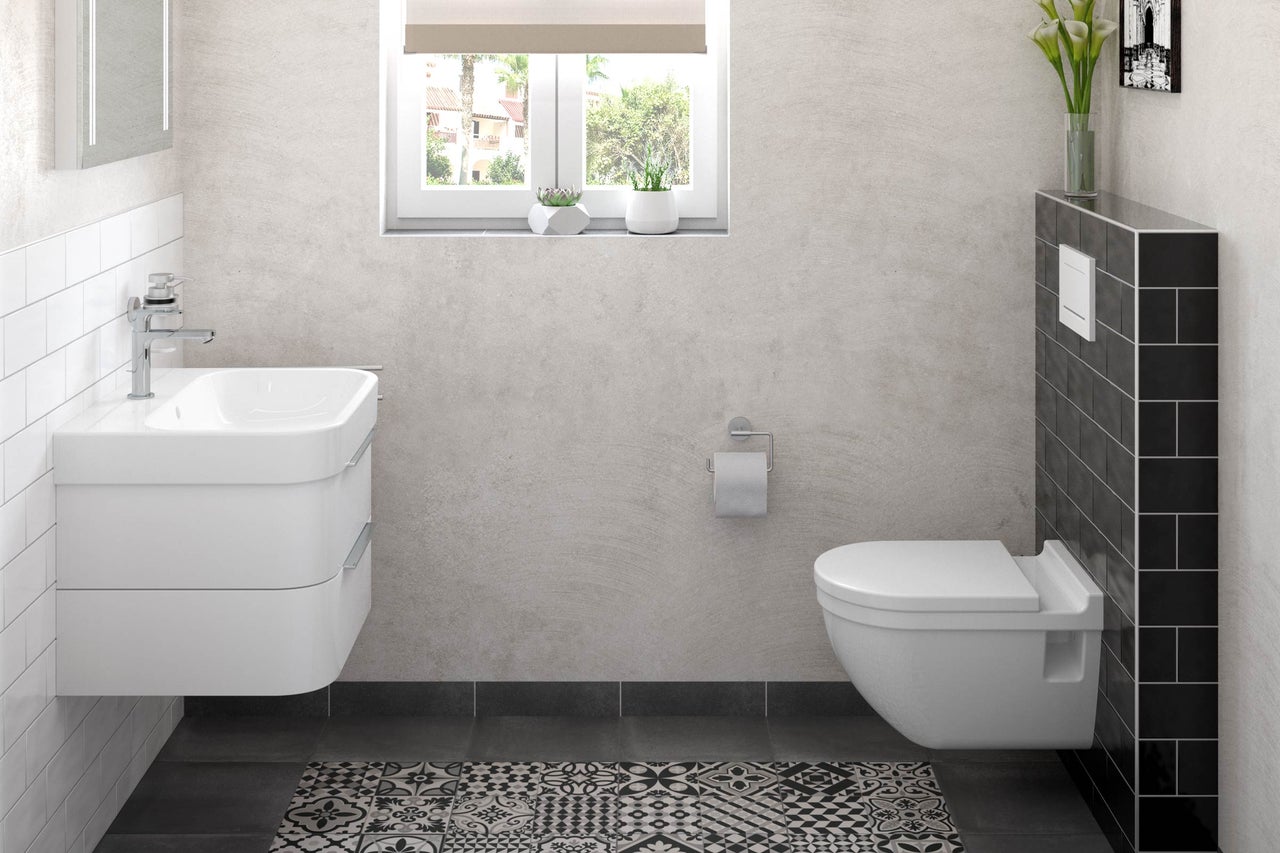 Salle de bain lumineuse avec lavabo, toilettes et carrelage à motifs.