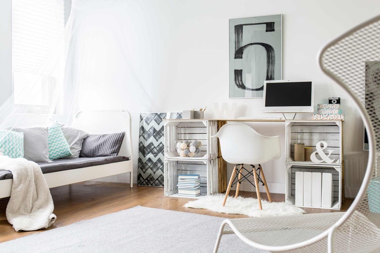 Chambre lumineuse avec lit, bureau en caisses en bois, chaise et tapis