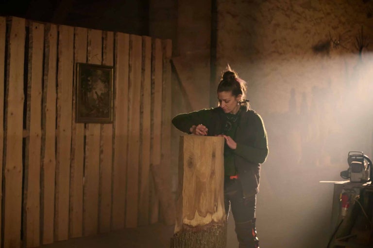 Frau bearbeitet Holzstamm in Werkstatt