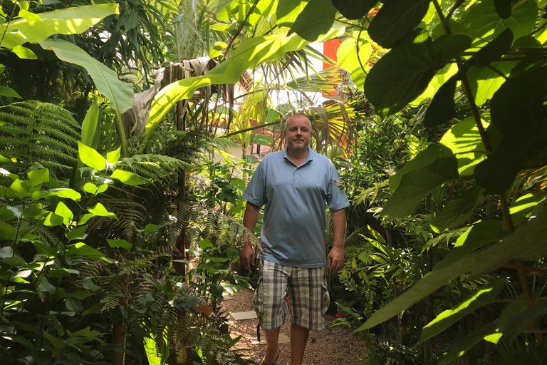 Homme debout dans un jardin luxuriant.
