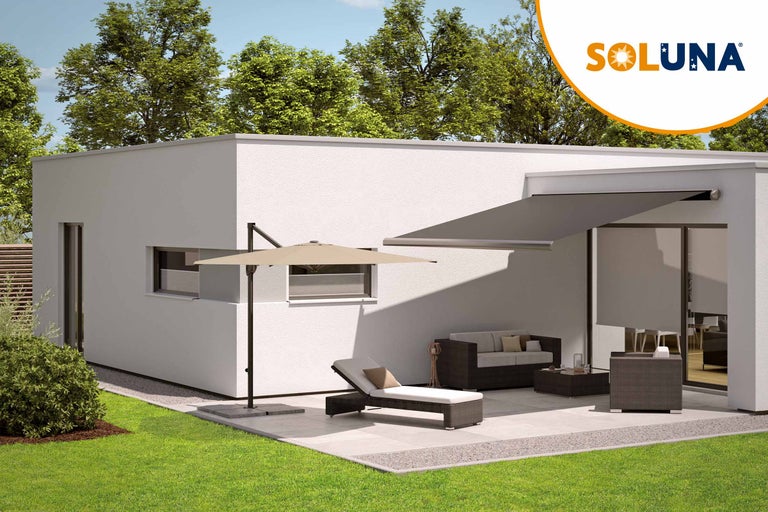 Terrasse avec store, parasol et mobilier de jardin devant une maison. Logo Soluna.
