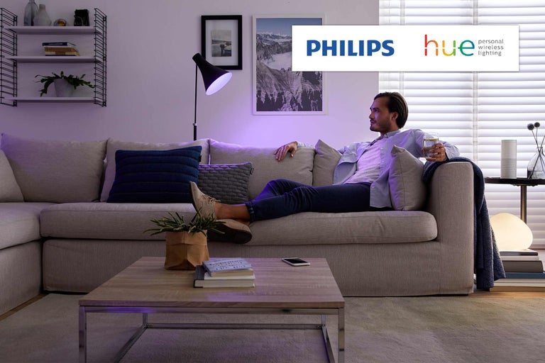 Salon avec éclairage Philips Hue et homme détendu sur le canapé