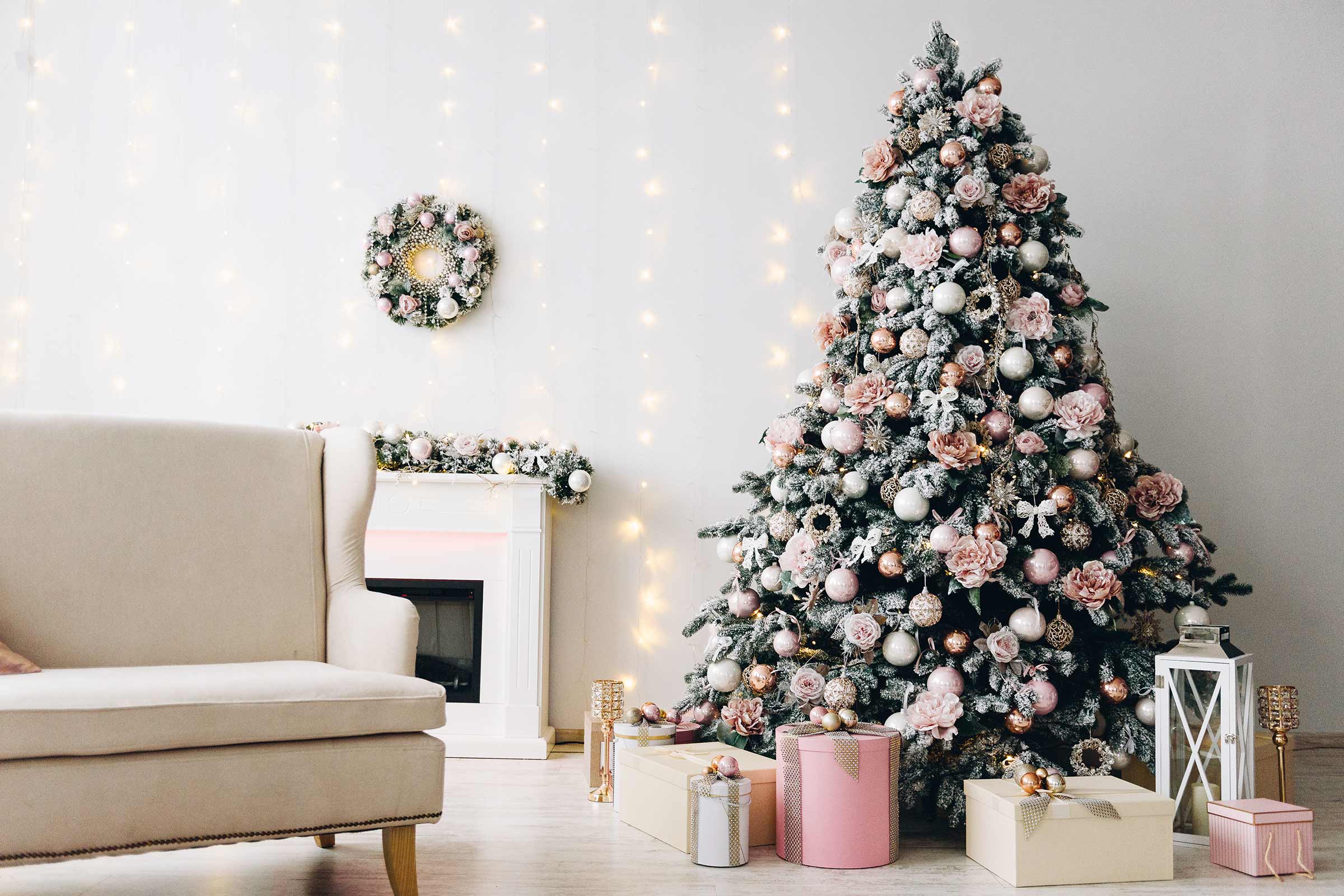 Dekorierter Weihnachtsbaum im Wohnzimmer mit Sessel, Kamin und Geschenken.