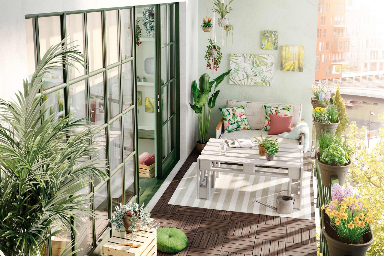 Balcon aménagé avec plantes, sièges et dalles de sol en bois.