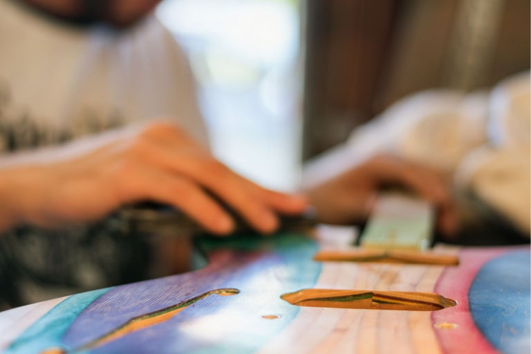 Handwerker bearbeitet ein buntes Holzbrett