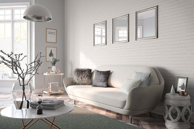 Salon lumineux avec canapé, table basse, table d'appoint et décorations murales devant un mur de briques