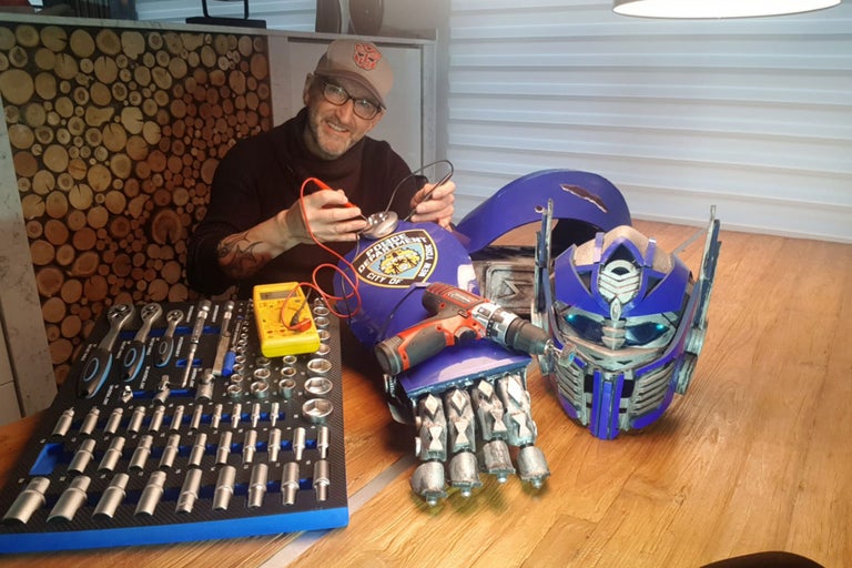 Mann repariert Transformers Kostüm mit Werkzeugen