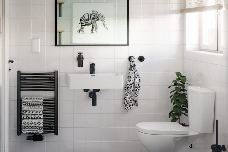 Salle de bain lumineuse avec lavabo, toilettes, sèche-serviettes et décorations