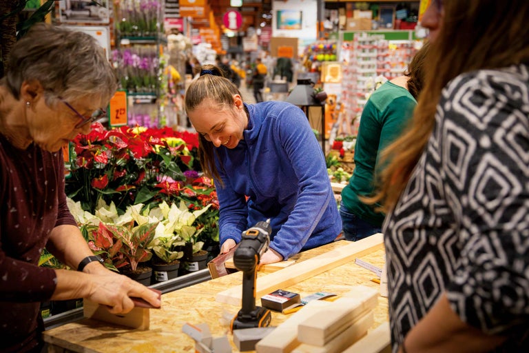 Des personnes travaillent le bois avec des outils sur une table dans le magasin Hornbach.
