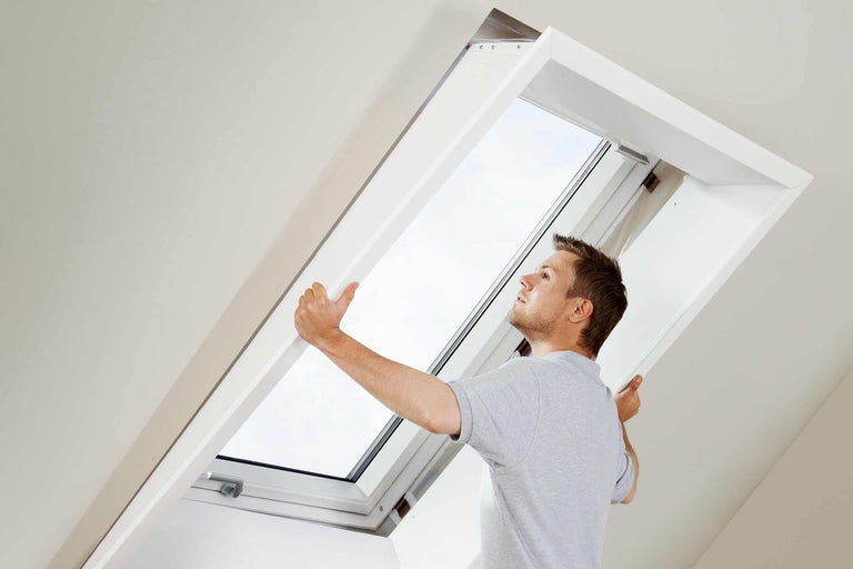 Ein Mann montiert ein Dachfenster im Dachgeschoss.