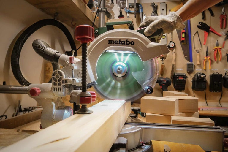 Scie à onglet Metabo coupant une pièce de bois dans un atelier.