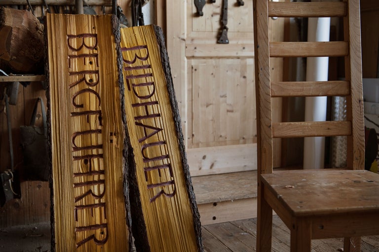Deux panneaux en bois avec les inscriptions Guide de montagne et Sculpteur à côté d'une chaise en bois.