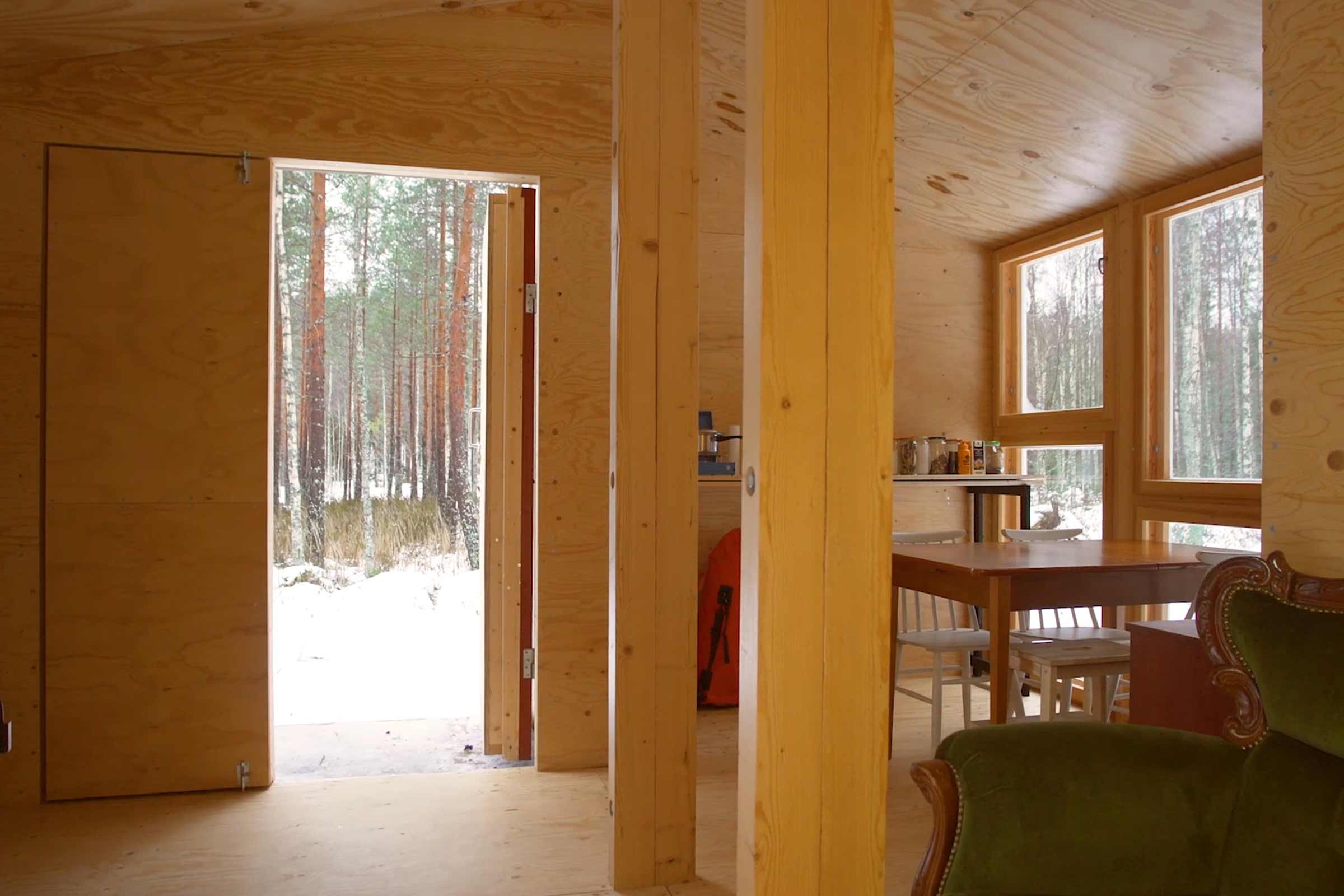 Intérieur d'une maison en bois avec vue sur une forêt hivernale.