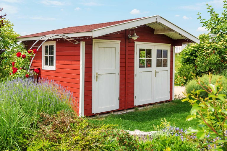 Petite cabane de jardin avec fenêtre et porte double dans le jardin