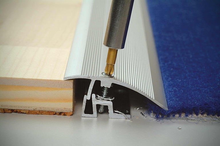 Montage d'un rail de transition entre revêtements de sol avec un tournevis