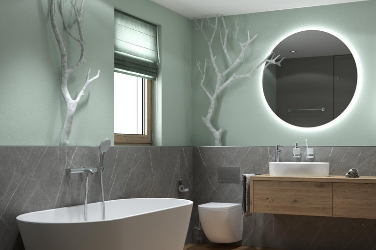 Salle de bains moderne et lumineuse avec baignoire îlot, WC suspendu, meuble en bois, miroir LED rond, murs aspect marbre et décor de branches.