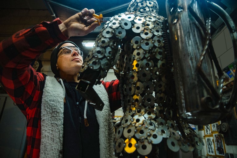 Un homme travaille une sculpture métallique dans un atelier.