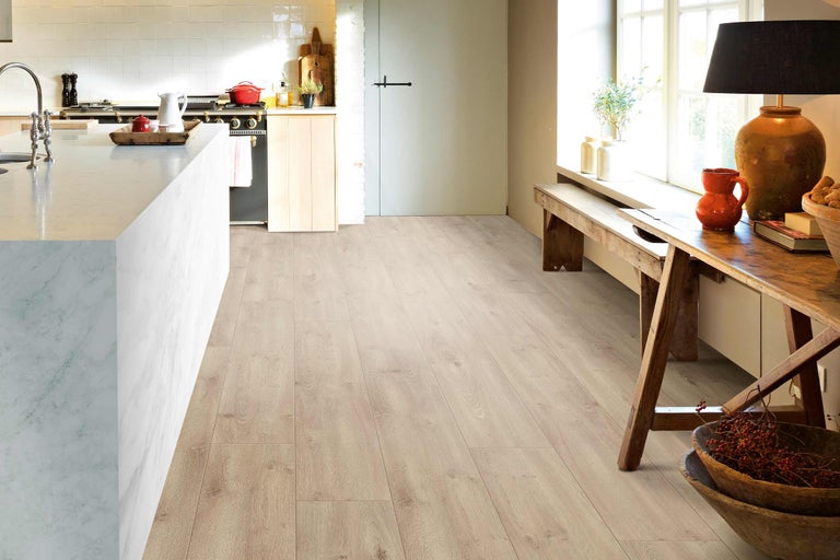 Heller Küchenraum mit Laminatboden in Holzoptik, Kücheninsel und Sitzbereich am Fenster.