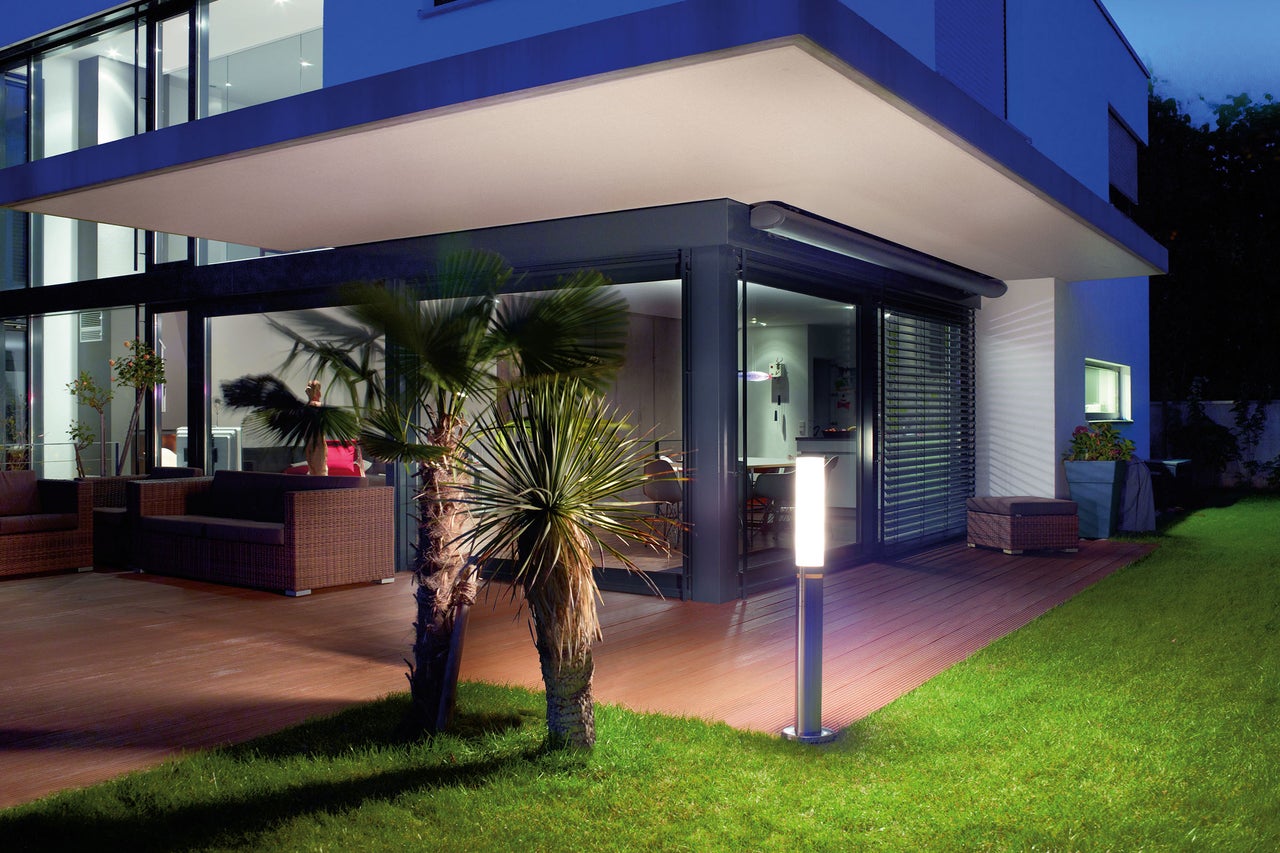 Terrasse moderne avec mobilier de salon, lames de terrasse et luminaire d'extérieur dans le jardin