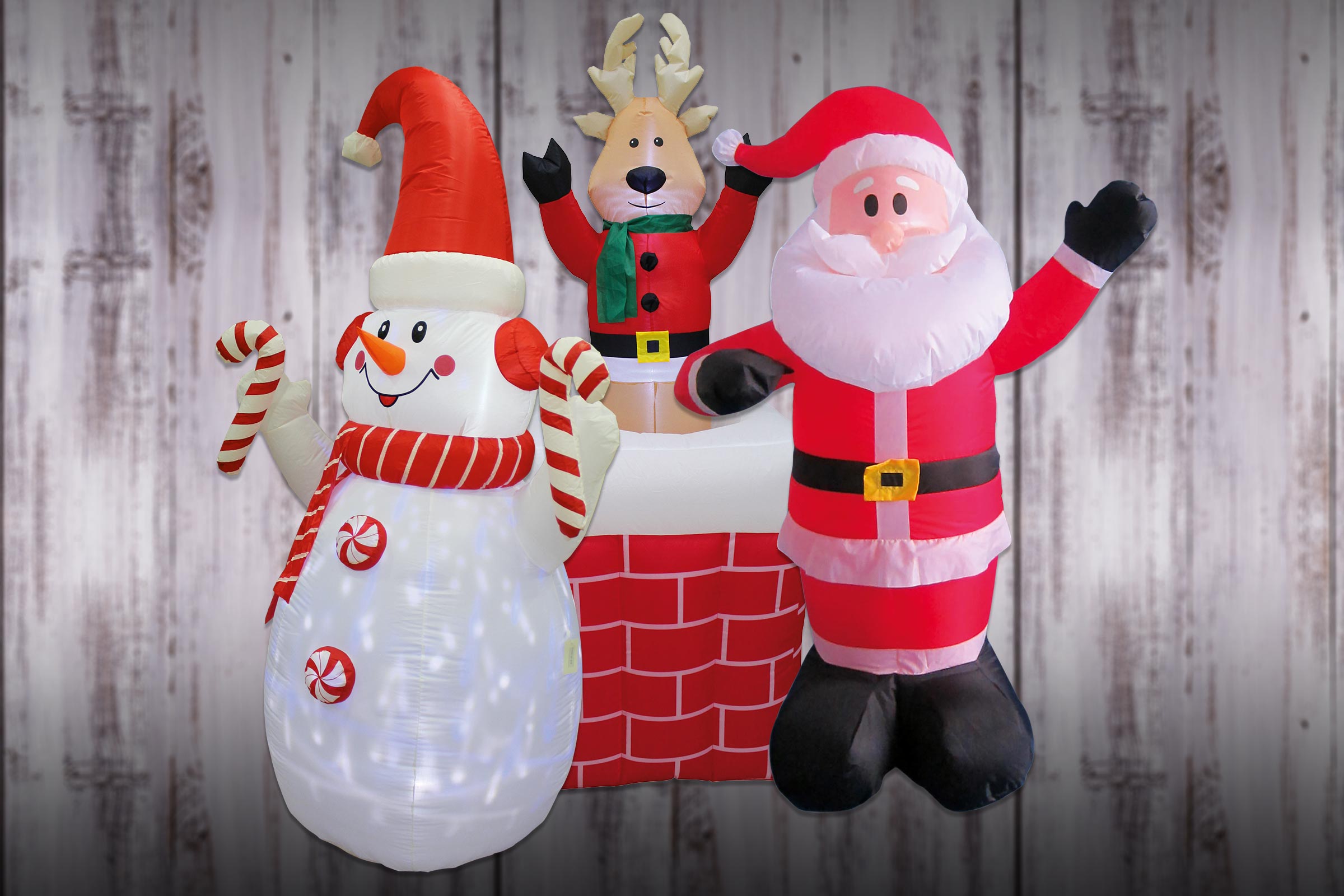 Aufblasbare Weihnachtsdekoration mit Schneemann, Rentier und Weihnachtsmann vor Holzwand