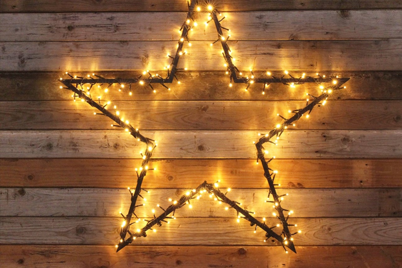 Étoile décorative avec des lumières devant un mur en bois