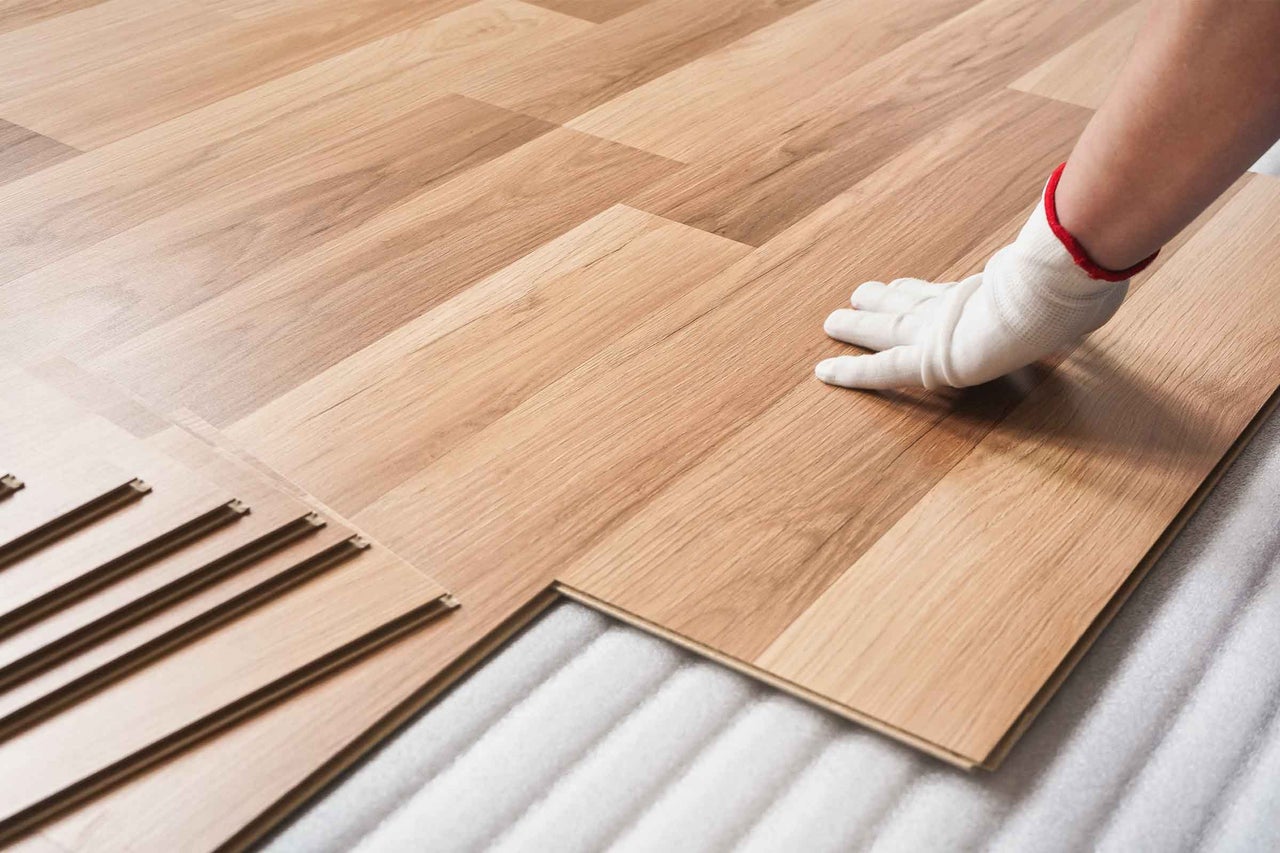 Verlegen von Laminatboden mit Handschuhen auf Dämmunterlage