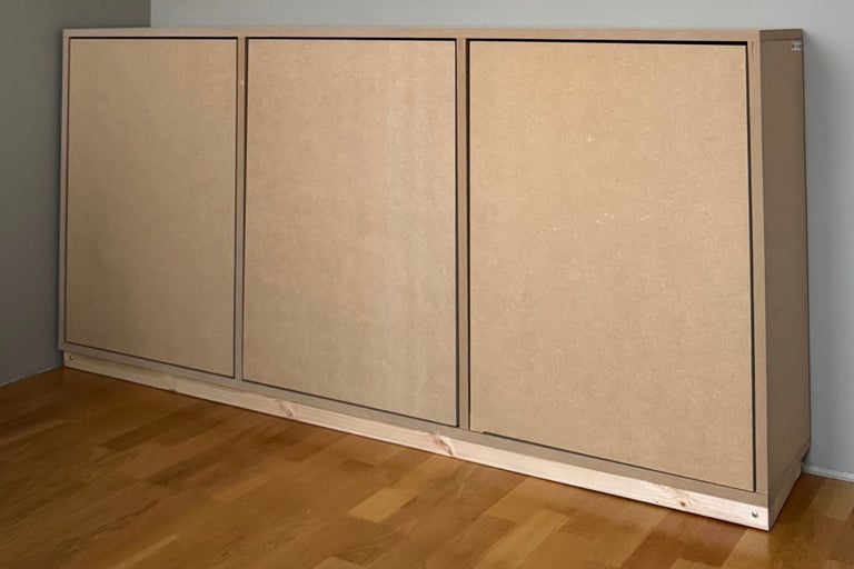 MDF-Wandschrank mit drei Türen und Holzsockel auf Holzboden