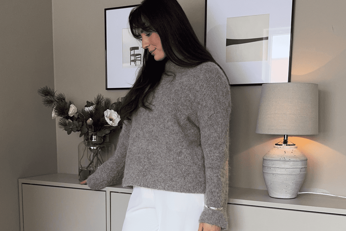 Wohnzimmer mit Kommode, Dekoration, Lampe und Frau im Pullover