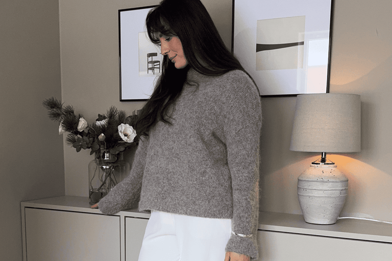 Wohnzimmer mit Kommode, Dekoration, Lampe und Frau im Pullover