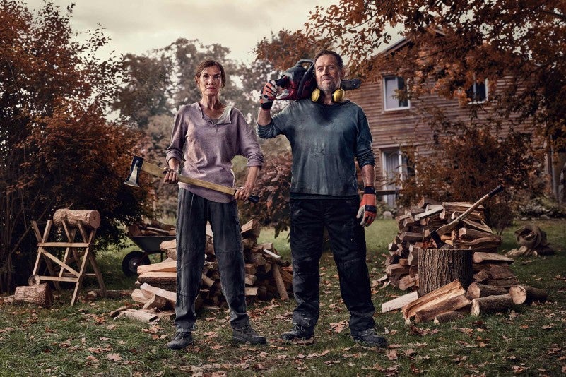 Ein Paar mit Axt und Kettensäge im Garten beim Holzspalten
