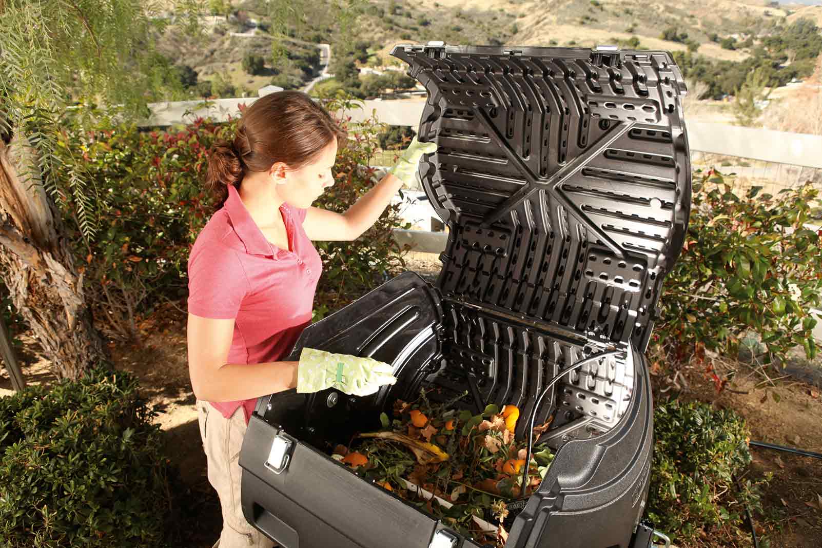 Femme remplissant un bac à compost dans le jardin avec des déchets de jardin.