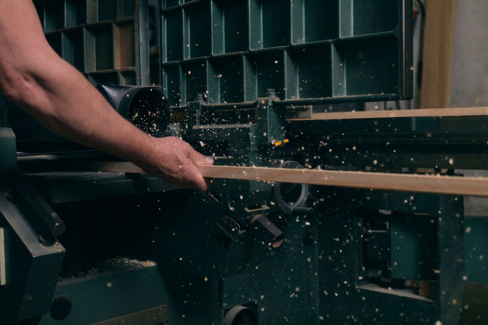 Eine Person bearbeitet ein Holzbrett mit einer Hobelmaschine.