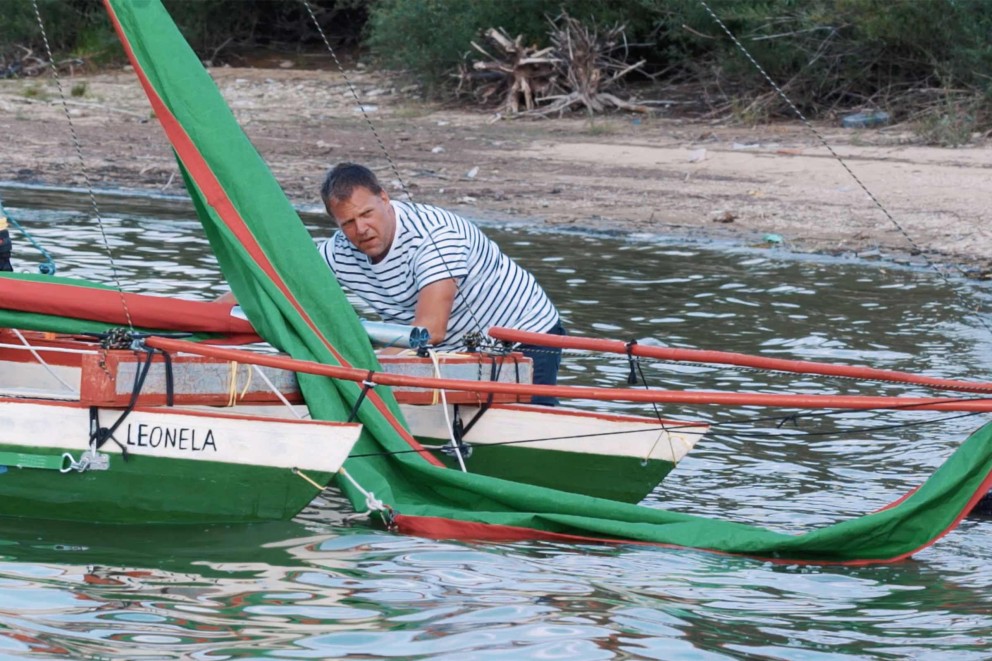 
				Michael Pietsch, debout dans l&lsquo;eau, amarre son catamaran.

			